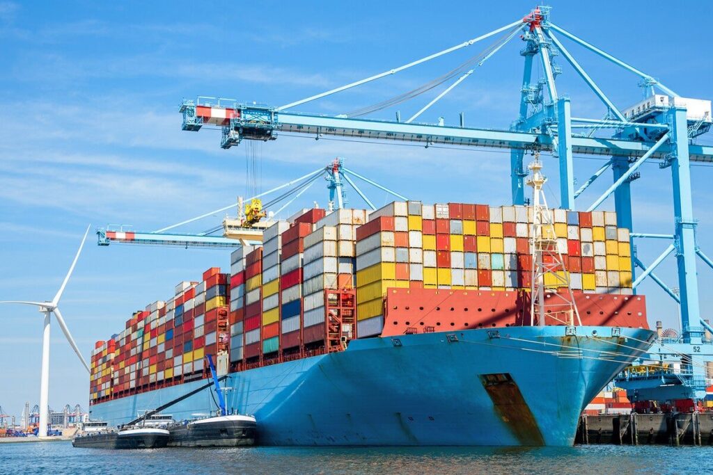 Container ship under light-blue ship-to-shore gantry cranes at a US container port